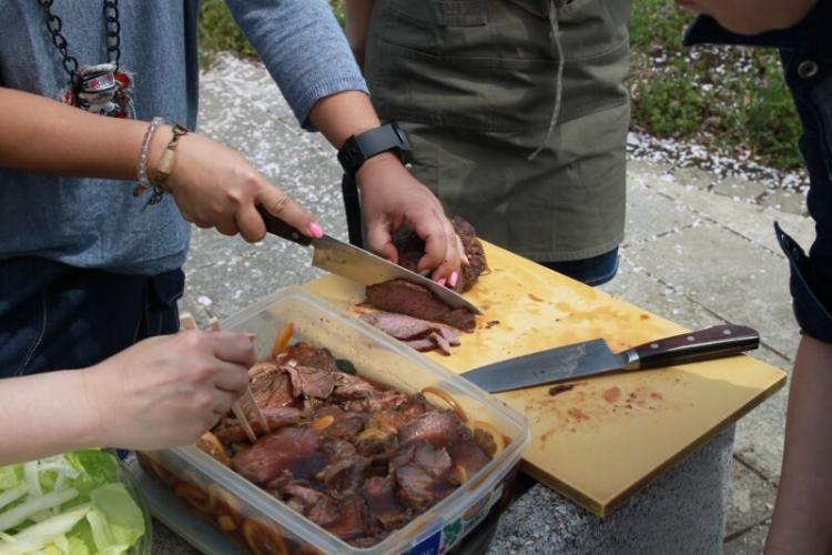 ブロック肉（塩、胡椒、クミン、ローズマリー等をもみ込んで一晩おく）を切ります