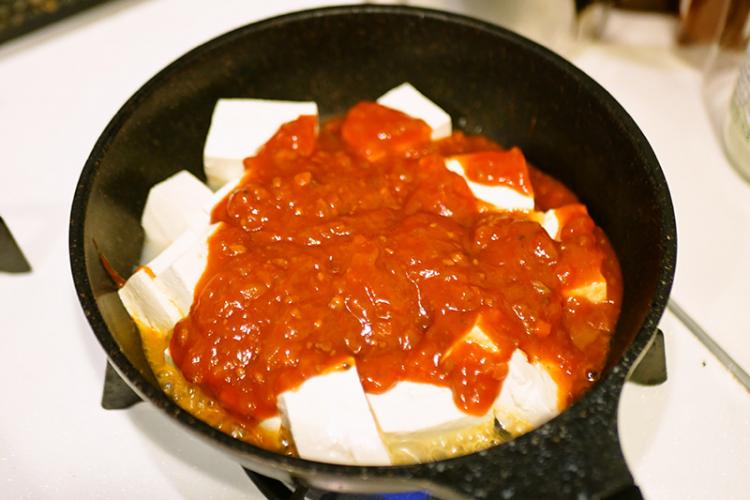 フッ素加工のフライパンに豆腐とミートソースを入れる